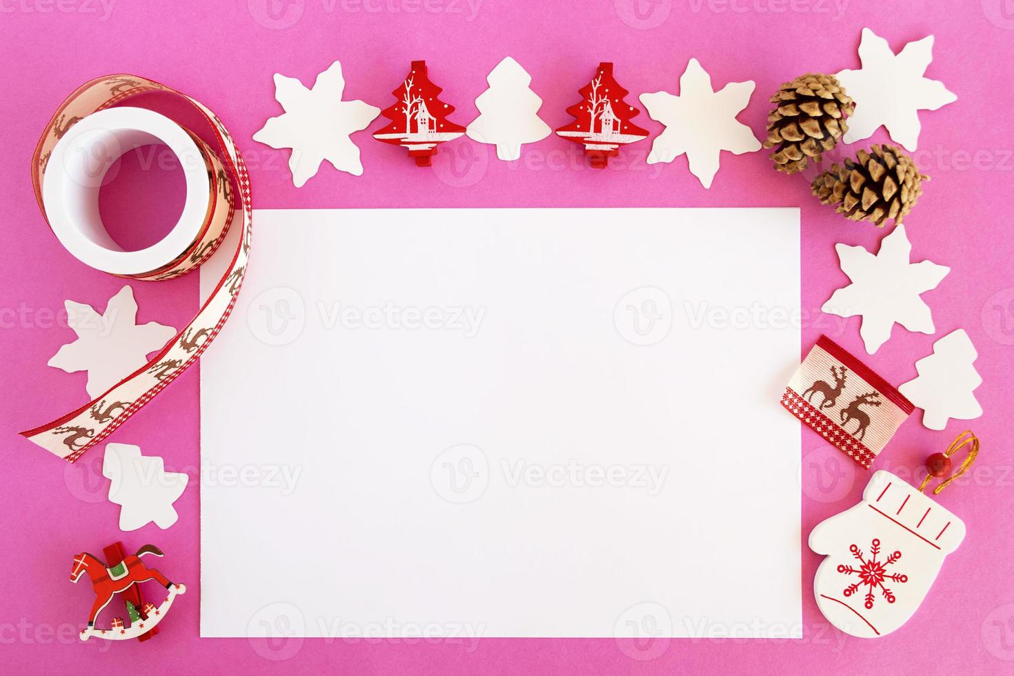 Top view on the Christmas decorations, pine cones and white sheet of paper on the pink background with copy space. photo