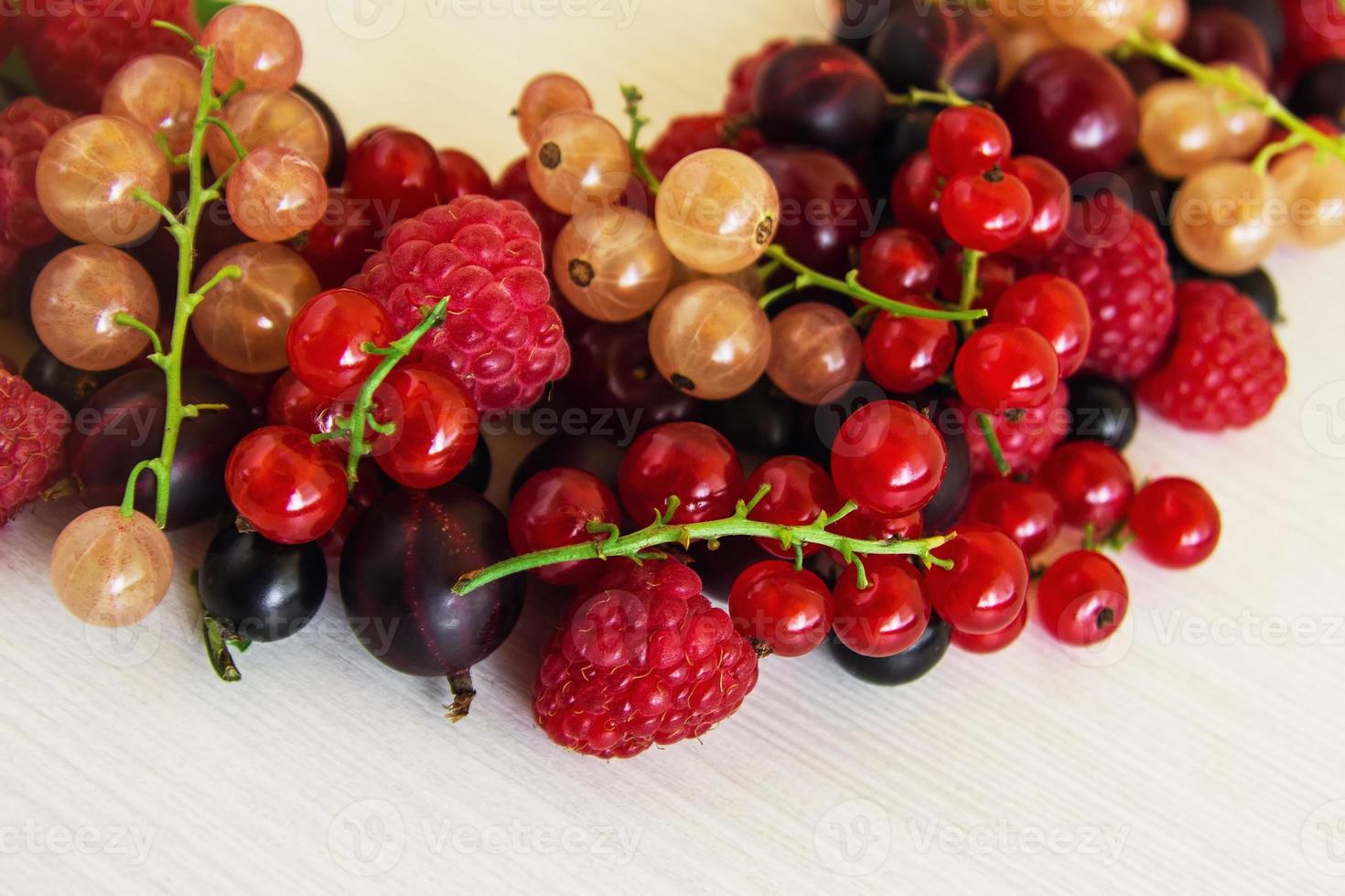 Mixed summer berries - raspberry, blackcurrant, redcurrant, white currant, gooseberry, cherry - on the white wooden background. photo