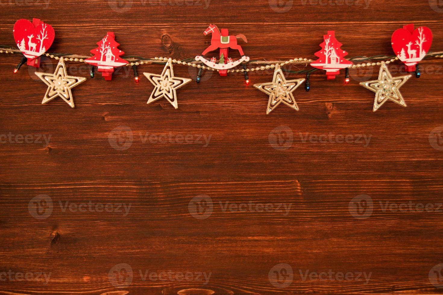 Red and white wooden Christmas decorations and Christmas lights on the brown wooden background, top view. photo