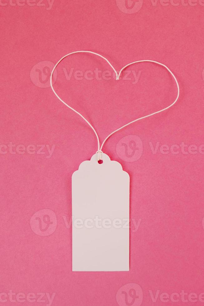 White blank paper price tag or label on the pink background, top view. photo