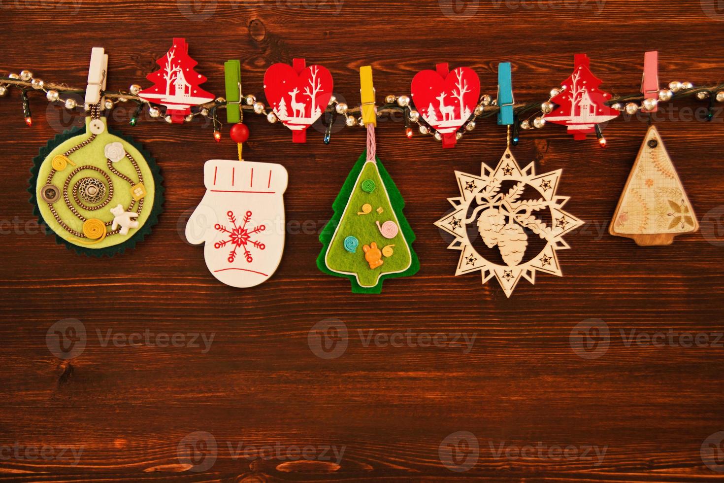 Wooden and felt colorful Christmas decorations and Christmas lights on a rope on the brown wooden background. photo