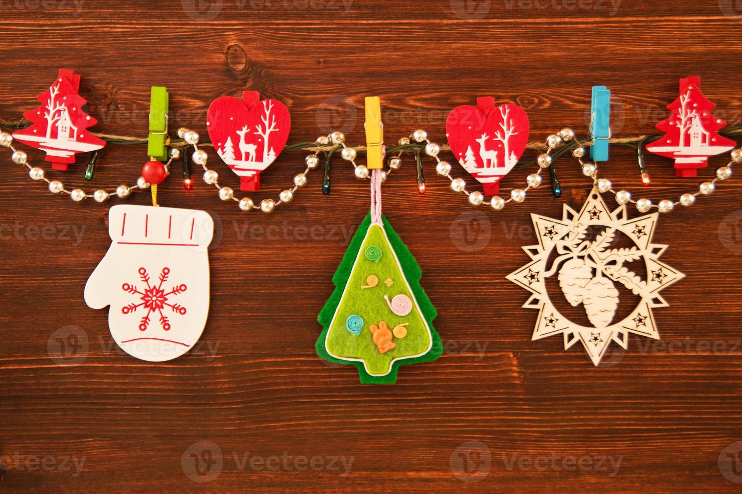 Wooden and felt colorful Christmas decorations and Christmas lights on a rope on the brown wooden background. photo