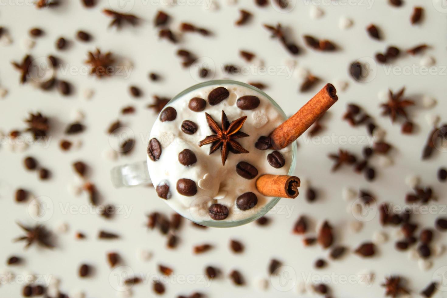 un vaso de helado con café, palitos de canela, granos de café y estrella de anís sobre el fondo blanco. foto