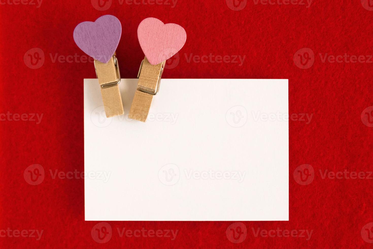 White sheet with pink and purple pins on the red background for Valentine Day. Copy space. photo