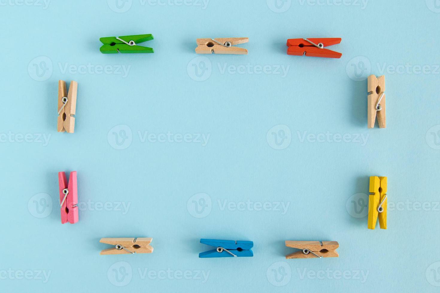 Frame from wooden colorful pins on the blue background with copy space. photo