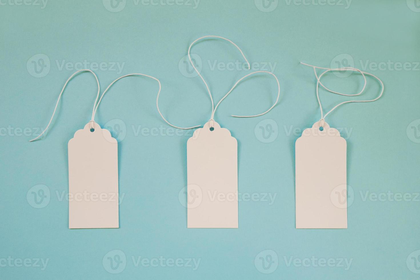 Three white blank paper price tags or labels set on the blue background, top view. photo