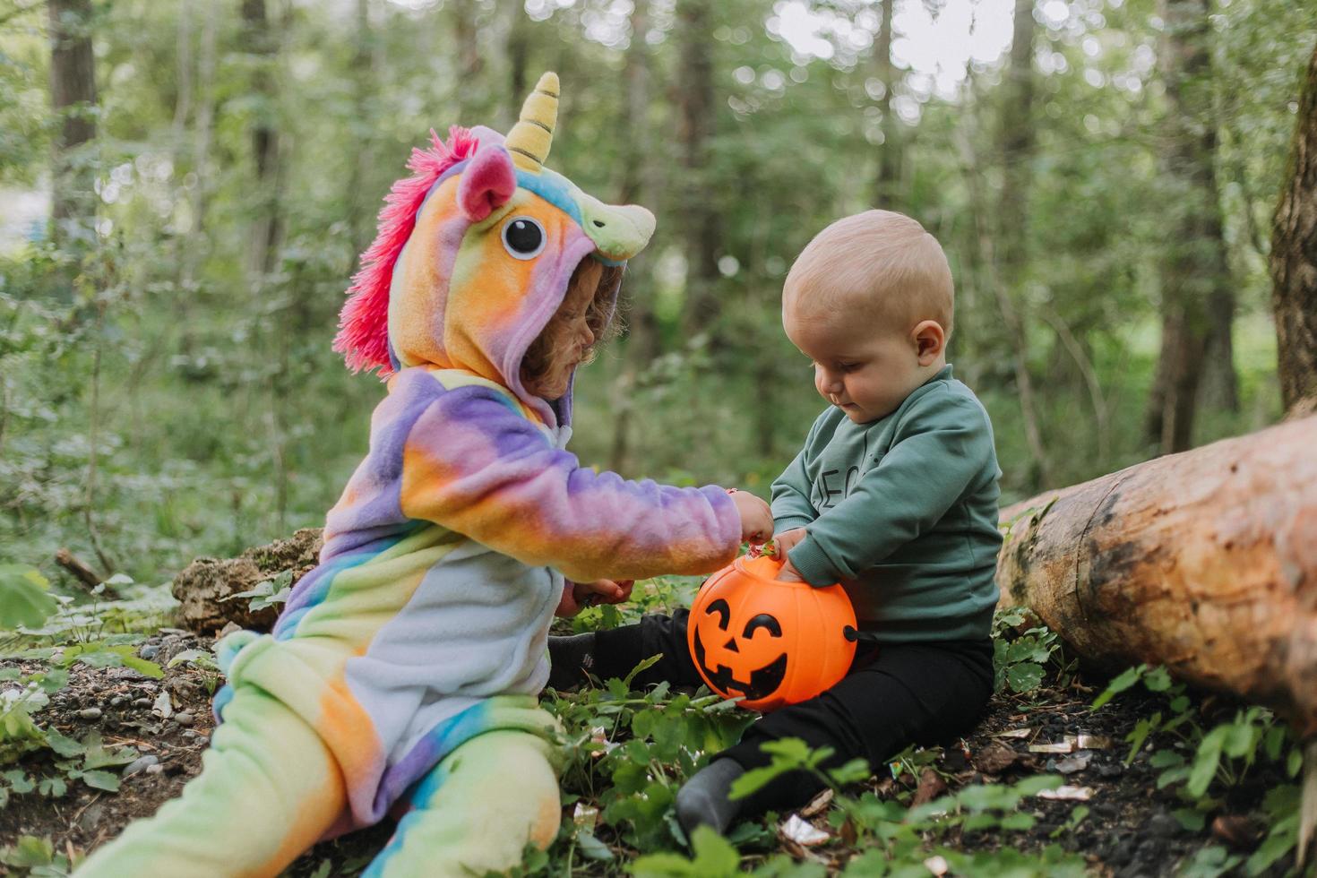 two children walk in the woods with a basket of Halloween candy photo