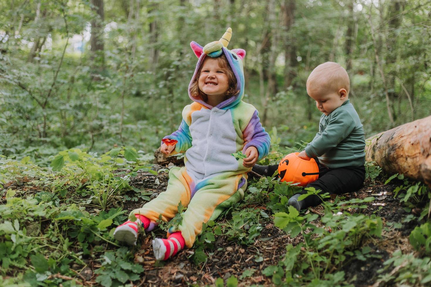 two children walk in the woods with a basket of Halloween candy photo