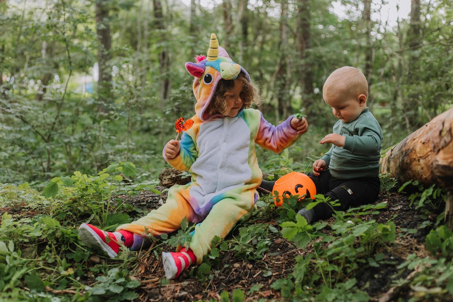 two children walk in the woods with a basket of Halloween candy photo