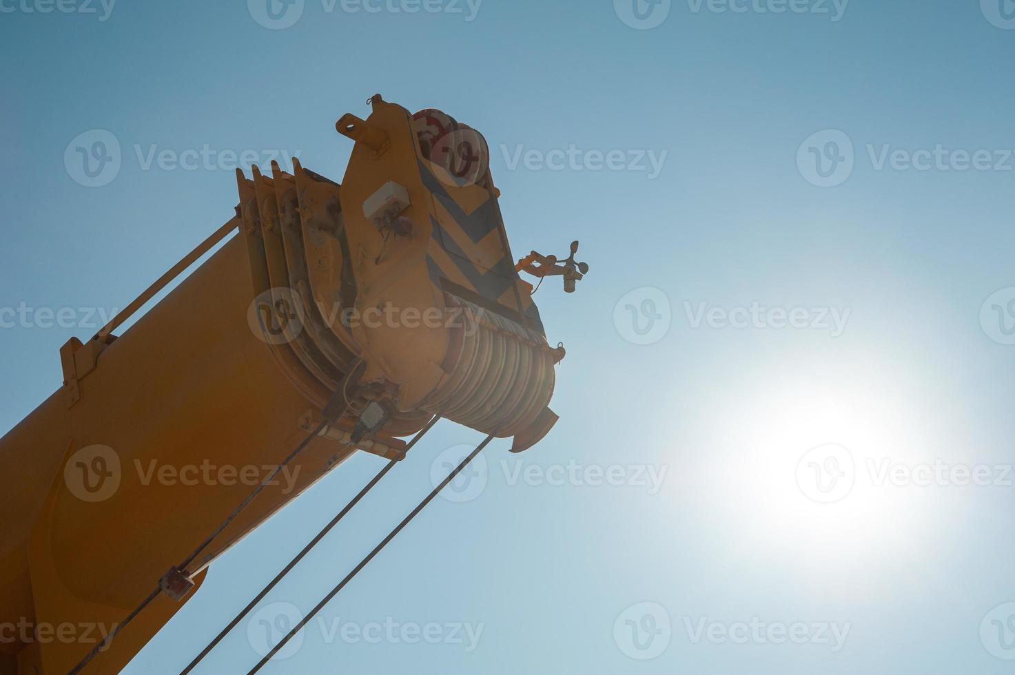 A closeup of a track crane tower against a sunny sky photo