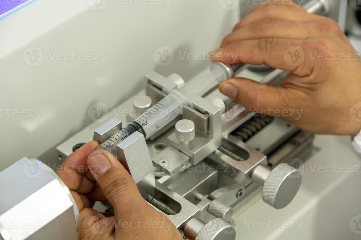 A closeup shot of hands working on a machine in a medical production warehouse for syringes photo