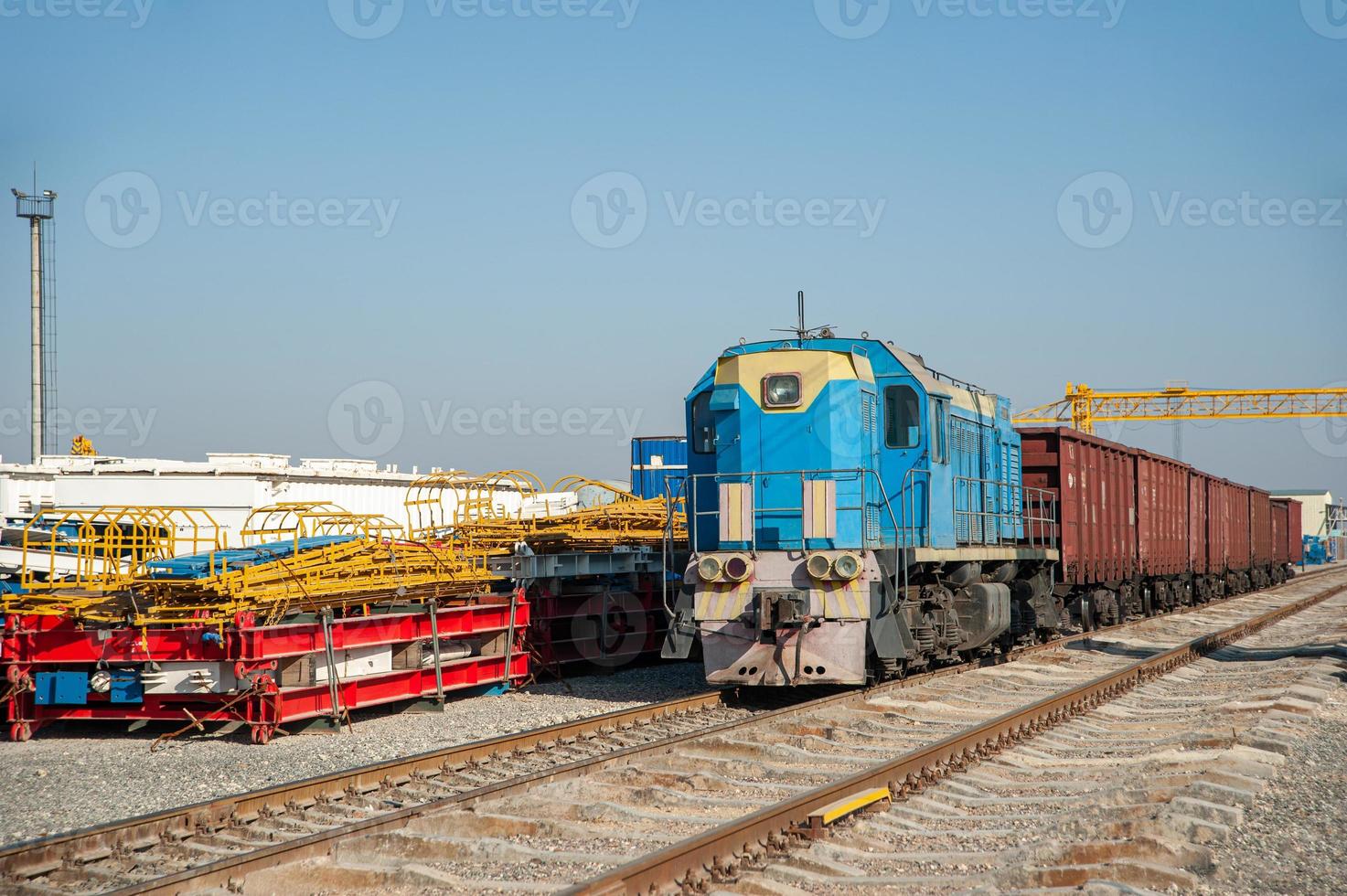 An old train on the railway tracks in the industrial construction on a sunny day photo