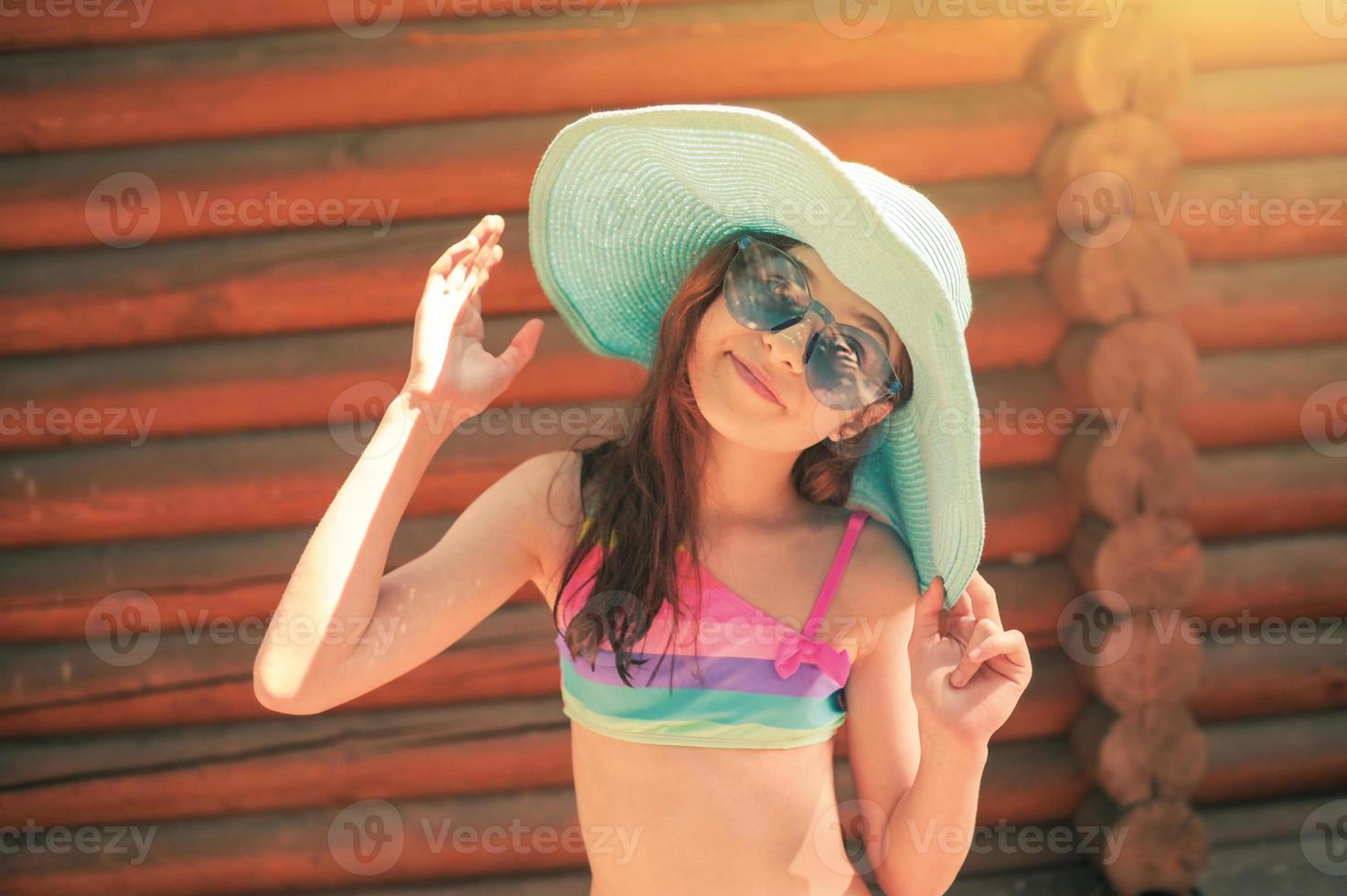 el concepto de vacaciones de verano. retrato de una adolescente con un traje de baño de arco iris y un sombrero azul. foto