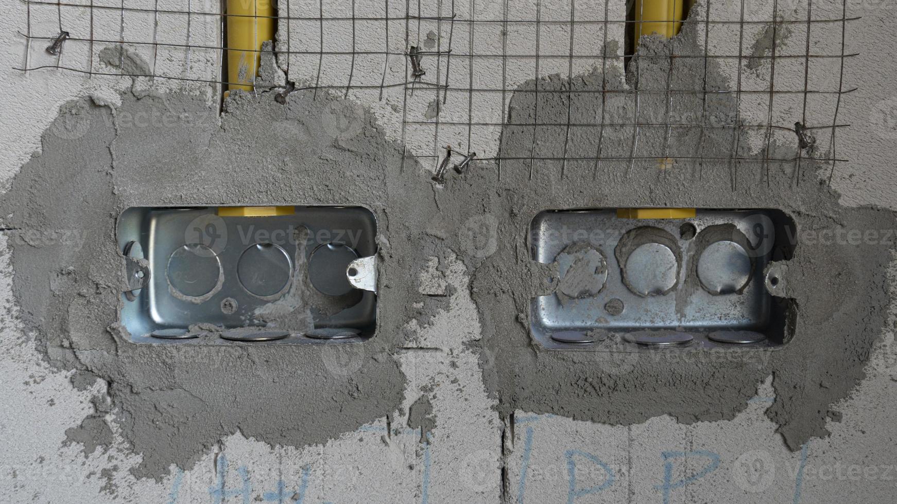 Two boxes of iron blocks that were buried in the walls of the house. with a yellow PVC pipe running down. Preparing for the electrical installation in the building. photo
