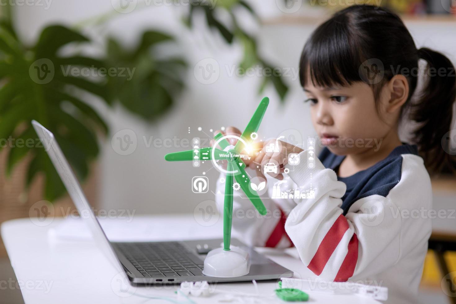 renewable energy, science, and technology concept - happy children with laptop computers, wind energy hologram,s and wind turbine models and icons. photo