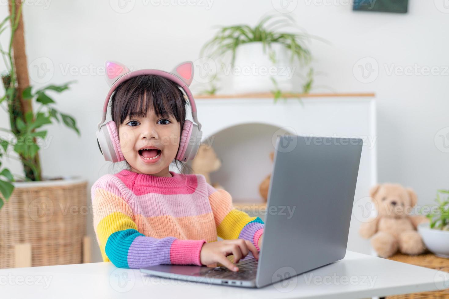 Smiling little Asian girl have a video call distant class with teacher using laptop, social distance during quarantine isolation during the Coronavirus photo