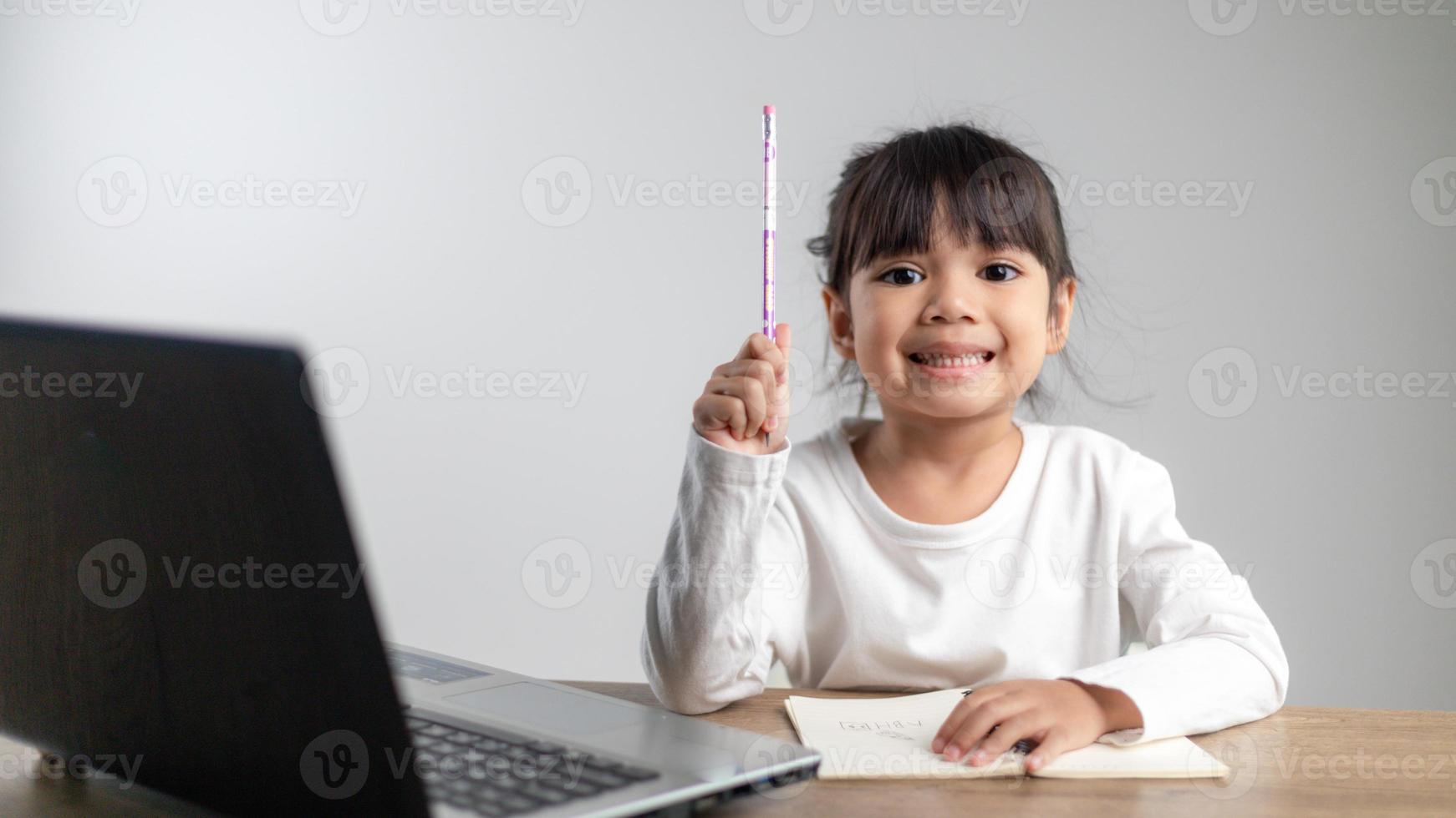 Smiling little Asian girl have video call distant class with teacher using laptop, social distance during quarantine isolation during the Coronavirus COVID-19 health care photo