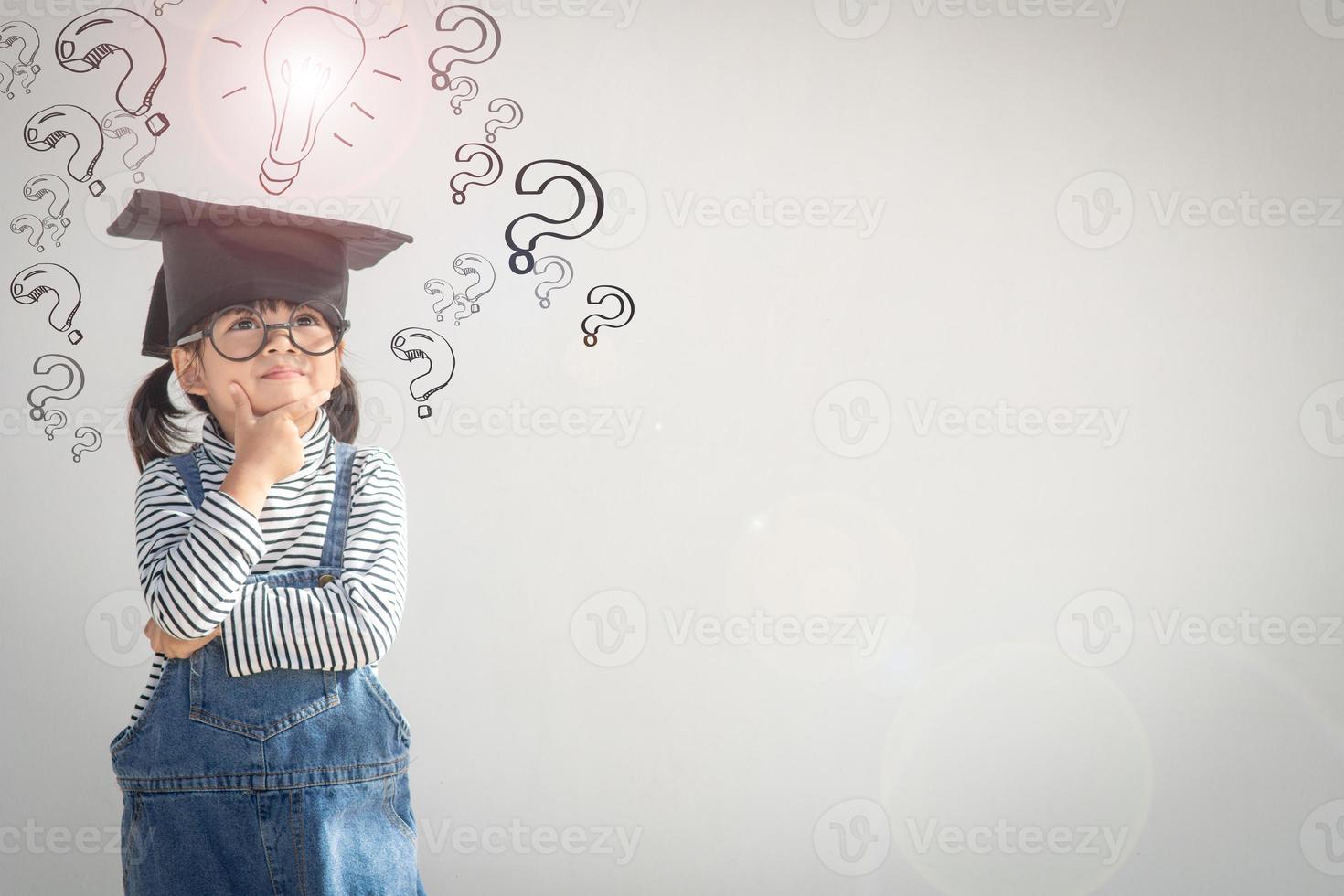 Happy Asian school kid graduate thinking with graduation cap photo