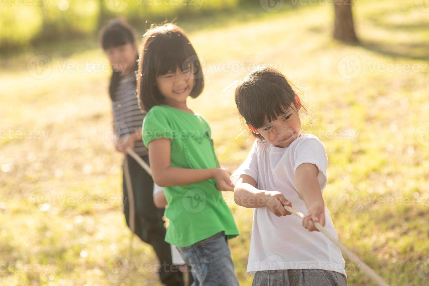 Children playing tug of war at the park on sunsut photo