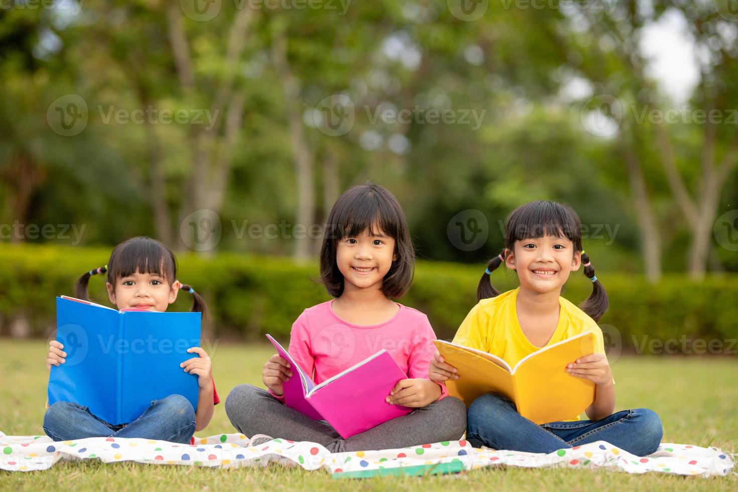 Three kids reading in the park. photo