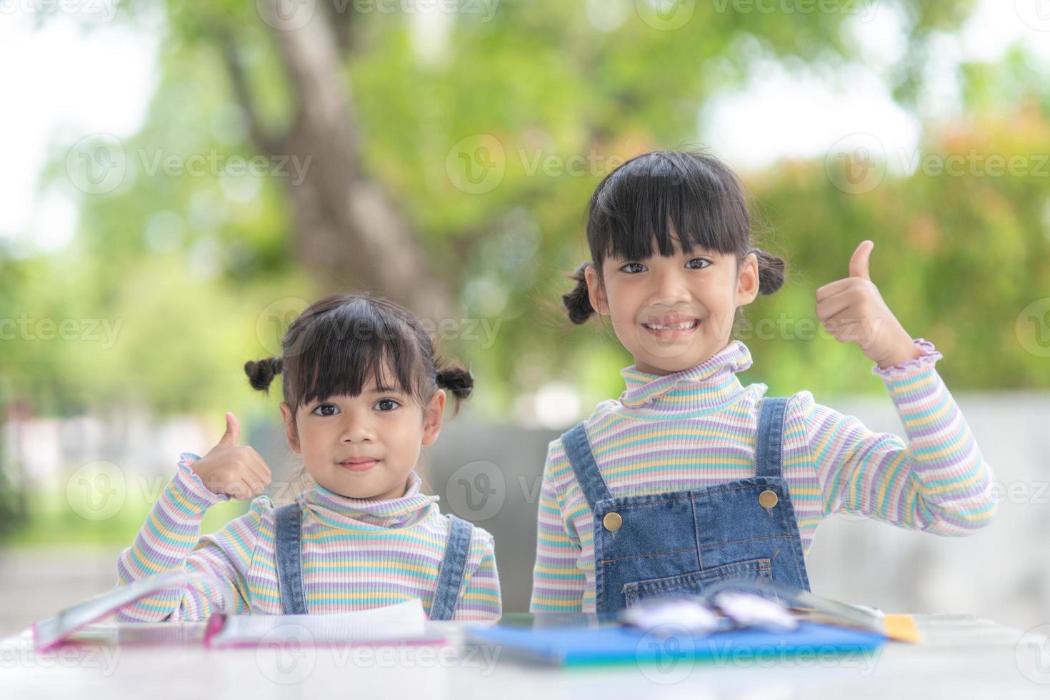 Two student little Asian girls reading the book on table photo