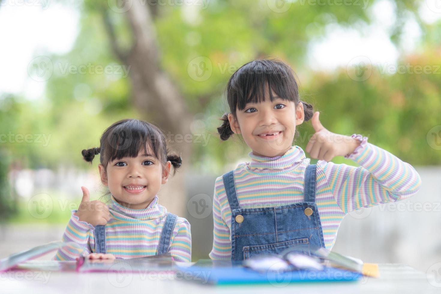 dos estudiantes niñas asiáticas leyendo el libro en la mesa foto