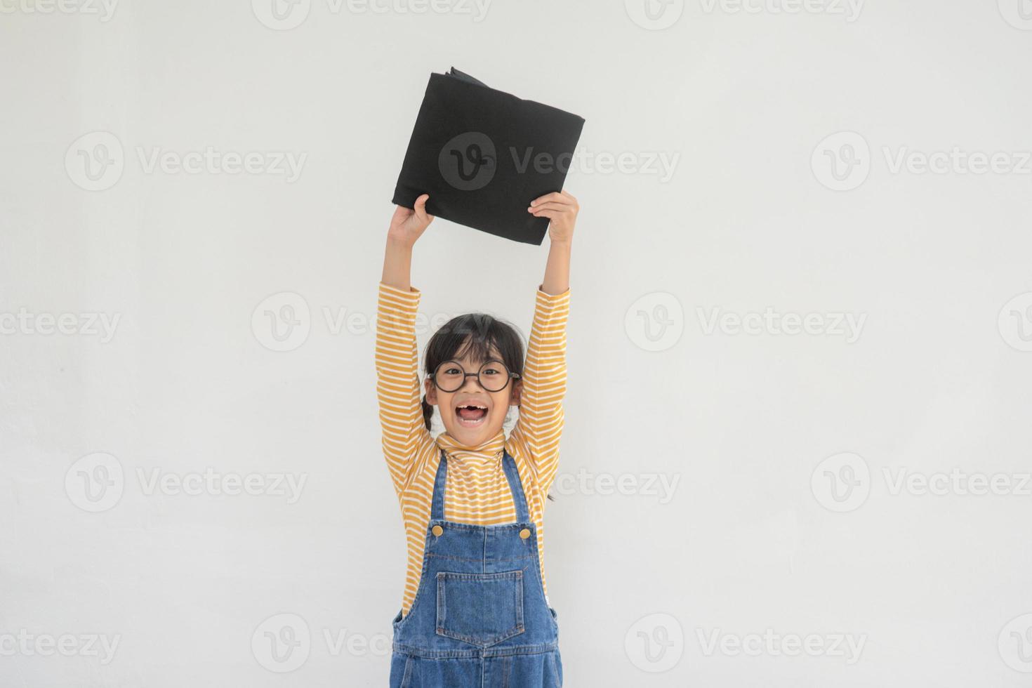 children girl wearing a graduate cap over white background very happy and excited doing winner gesture with arms raised, smiling and screaming for success. Celebration concept. photo