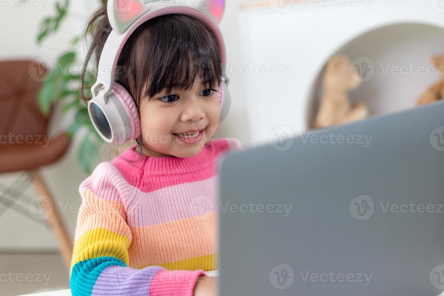 Smiling little Asian girl have a video call distant class with teacher using laptop, social distance during quarantine isolation during the Coronavirus photo