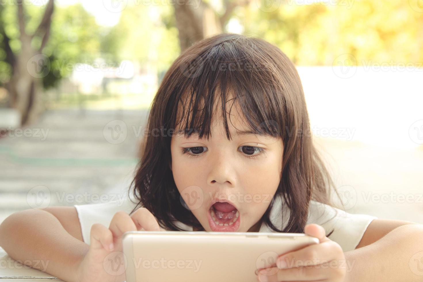 Shocked and surprised little girl on the internet with digital tablet computer concept for amazement, astonishment, making a mistake, stunned and speechless or seeing something he should not see photo