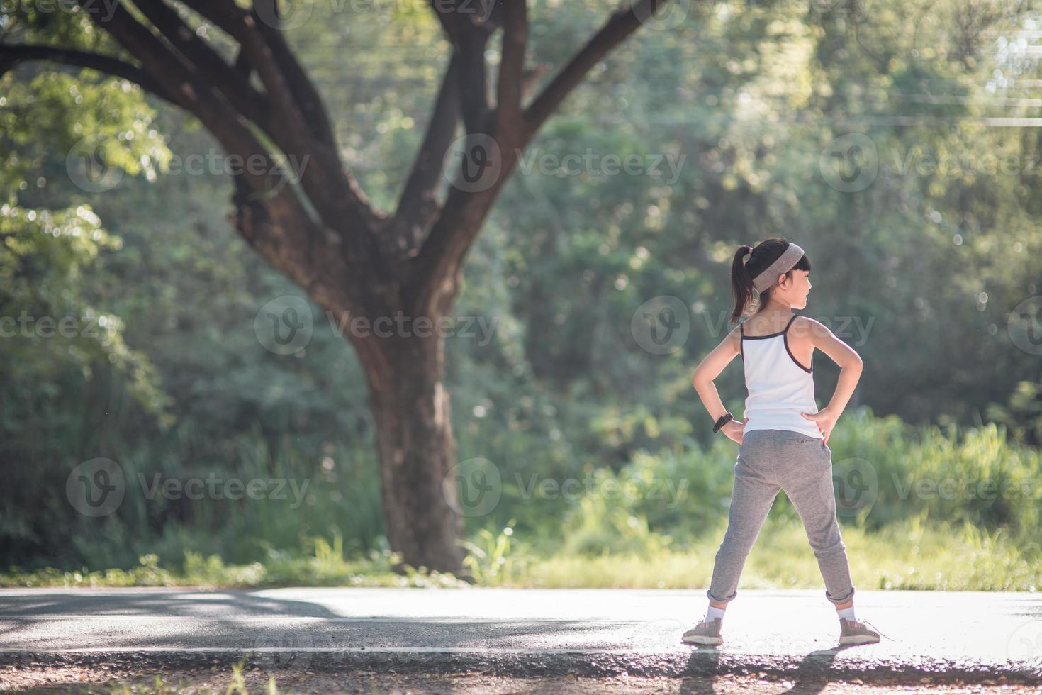 una niña haciendo ejercicio bajo la luz brillante del sol. foto