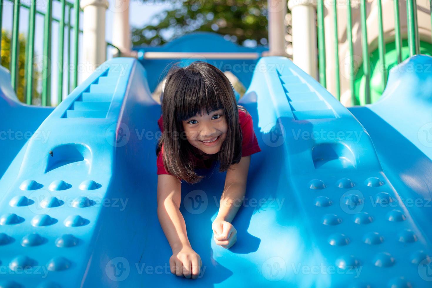 Cute little girl having fun on a playground outdoors in summer photo