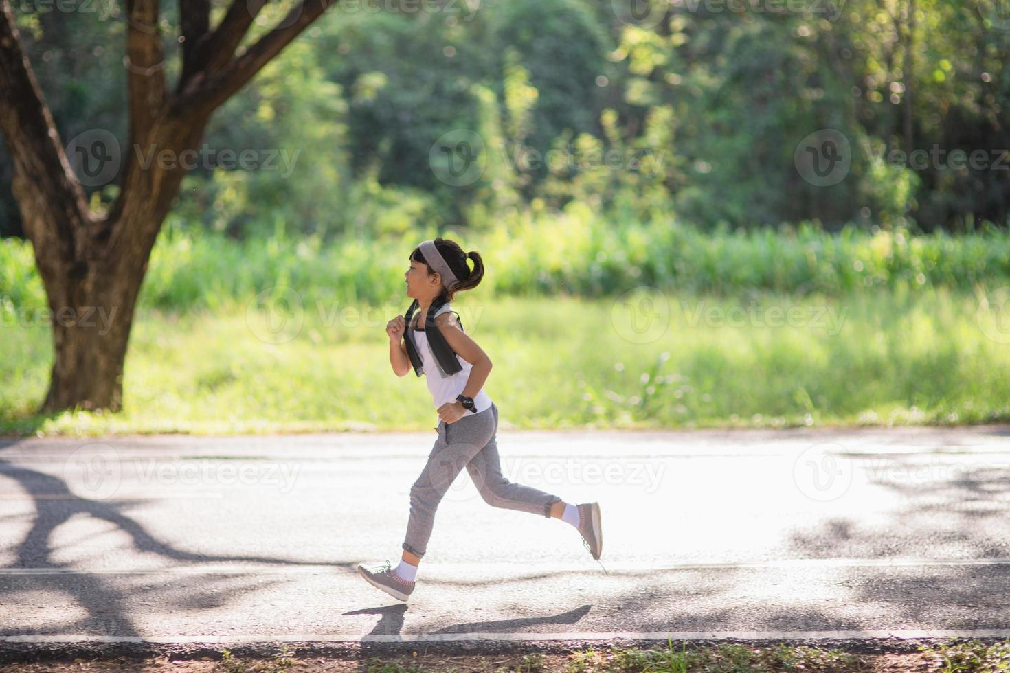 happy child girl running in the park in summer in nature. warm sunlight flare. asian little is running in a park. outdoor sports and fitness, exercise and competition learning for kid development. photo