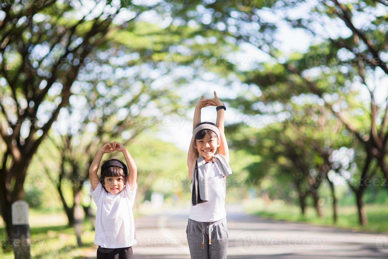 Two asian little girls having fun and running together in the park in vintage color tone photo