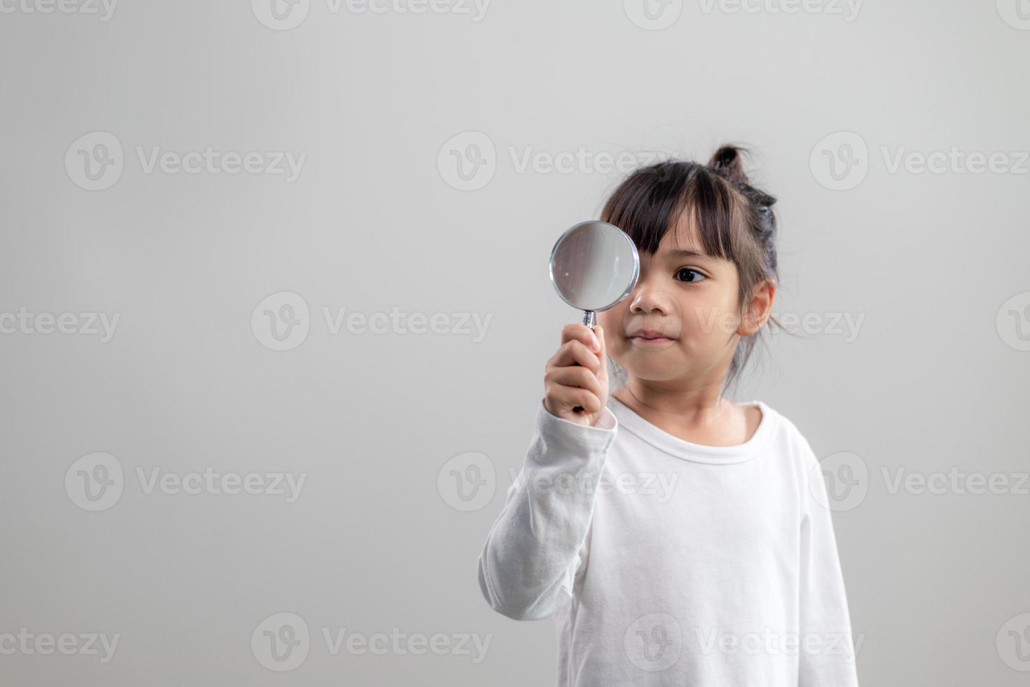 little girl looking through a magnifying glass photo