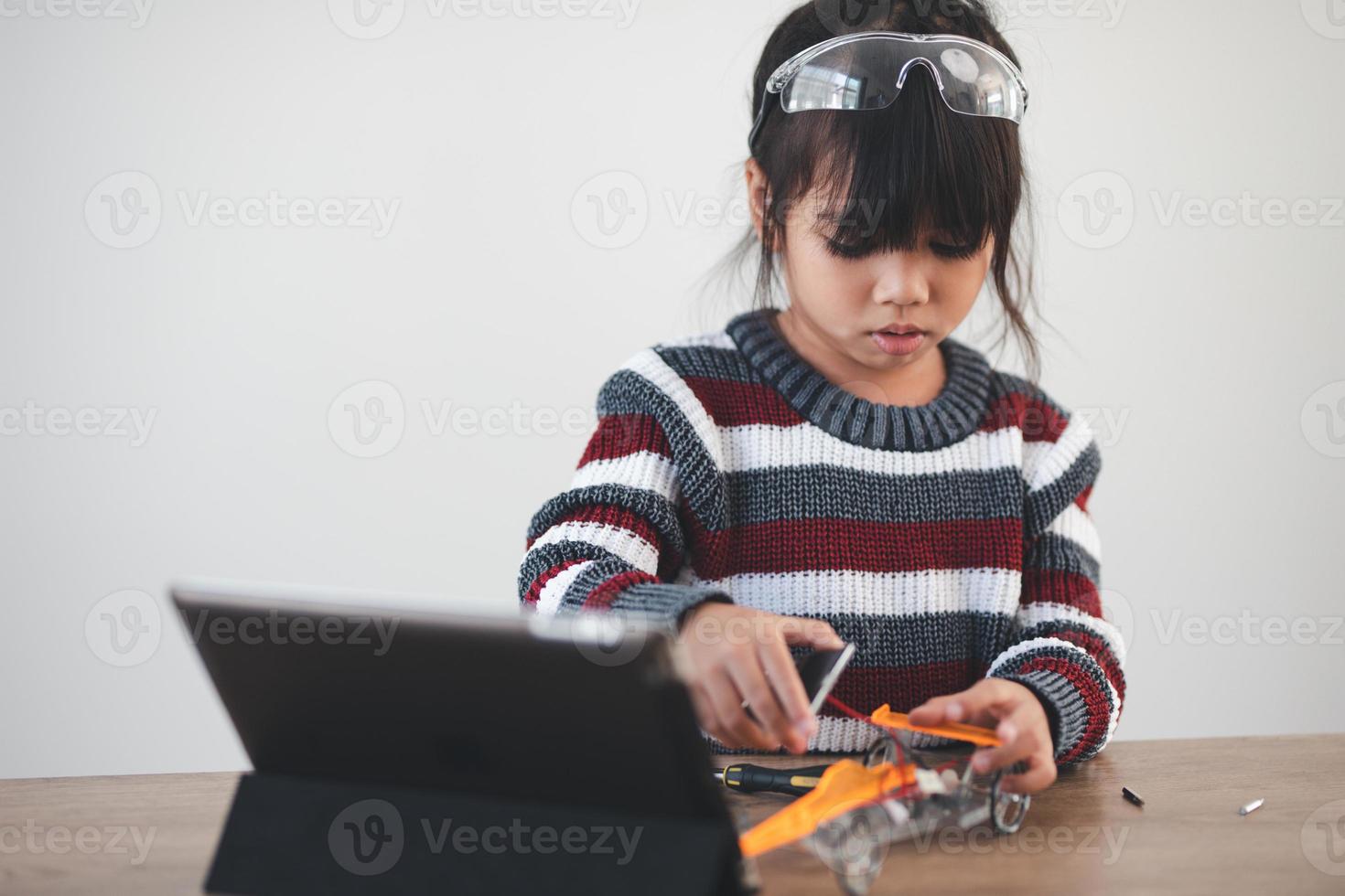 niño ingenioso construyendo autos robot en casa foto