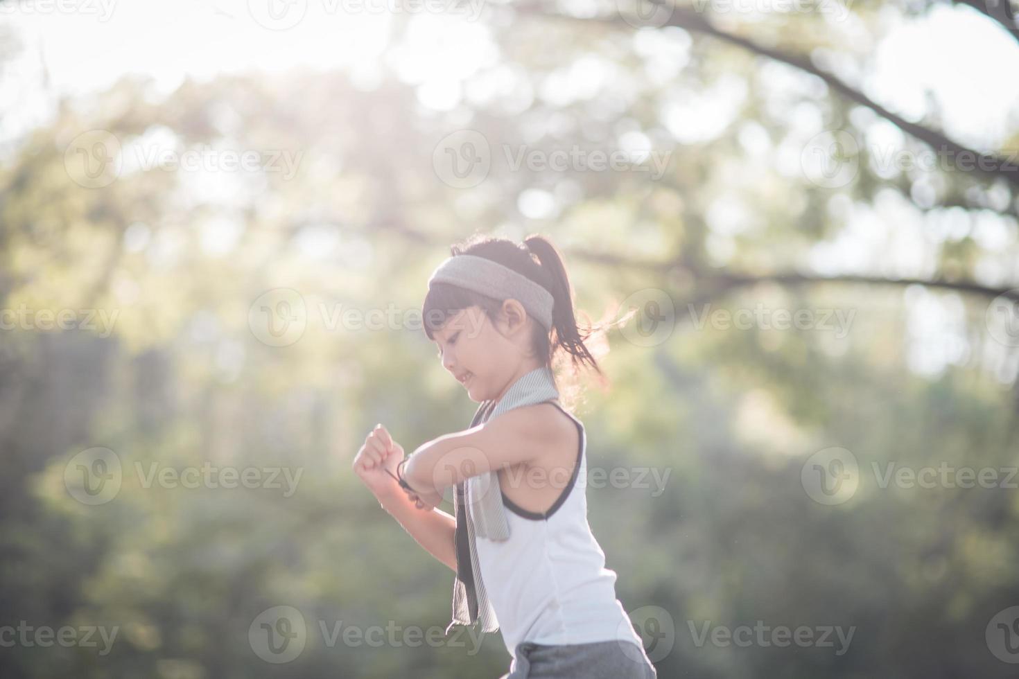 happy child girl running in the park in summer in nature. warm sunlight flare. asian little is running in a park. outdoor sports and fitness, exercise and competition learning for kid development. photo