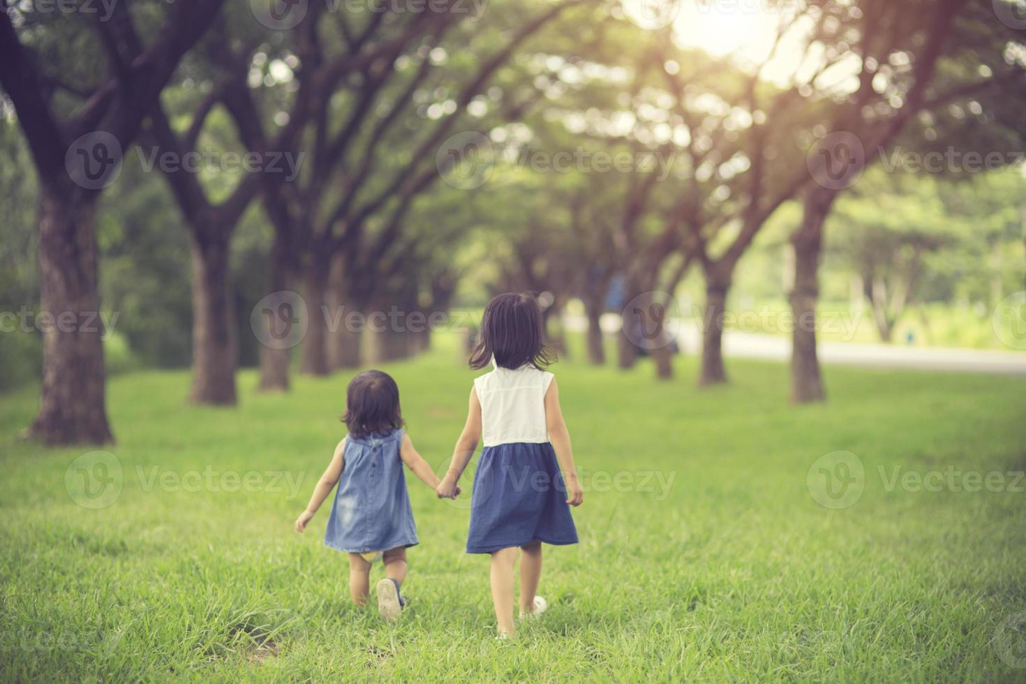 Two little sisters holding each other hands and running forward.Vintage color photo