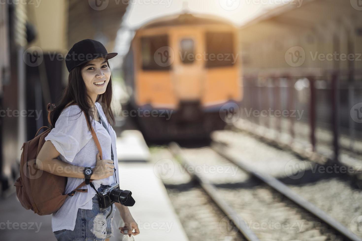 Traveler woman walking and waits train on railway platform photo