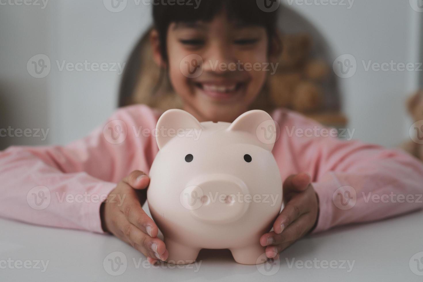 Little Asian girl saving money in a piggy bank, learning about saving, Kid save money for future education. Money, finances, insurance, and people concept photo