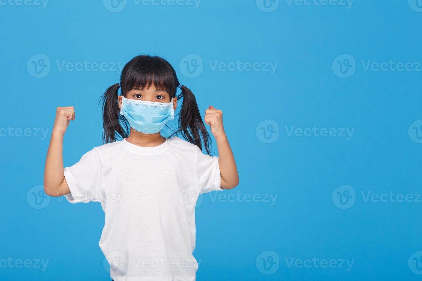 asia girl wearing mask to protect against Coronavirus, girl show a fist encourage to fight contagious disease concept stop virus Covid 19 outbreak to win on white background photo
