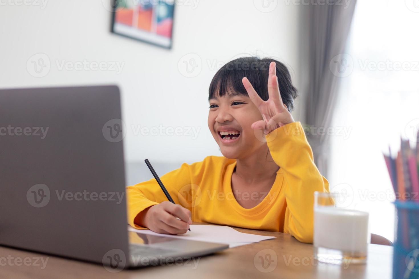 Asian girl student online learning class study online video call zoom teacher, Happy girl learn english language online with laptop at home.New normal.Covid-19 coronavirus.Social distancing.stay home photo