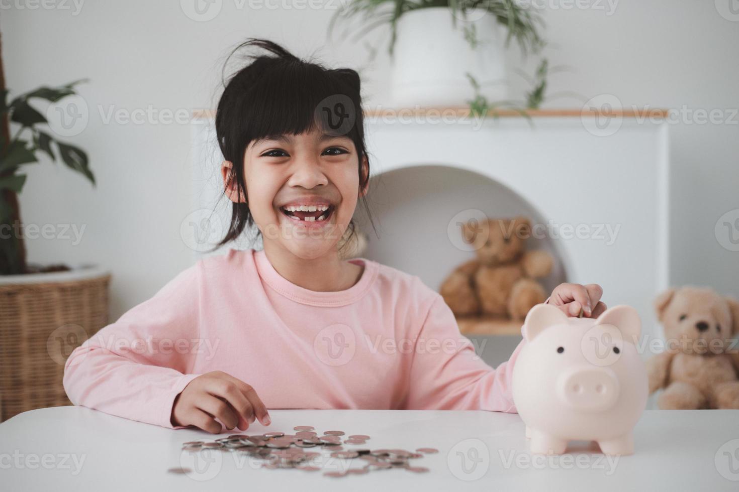 Little Asian girl saving money in a piggy bank, learning about saving, Kid save money for future education. Money, finances, insurance, and people concept photo