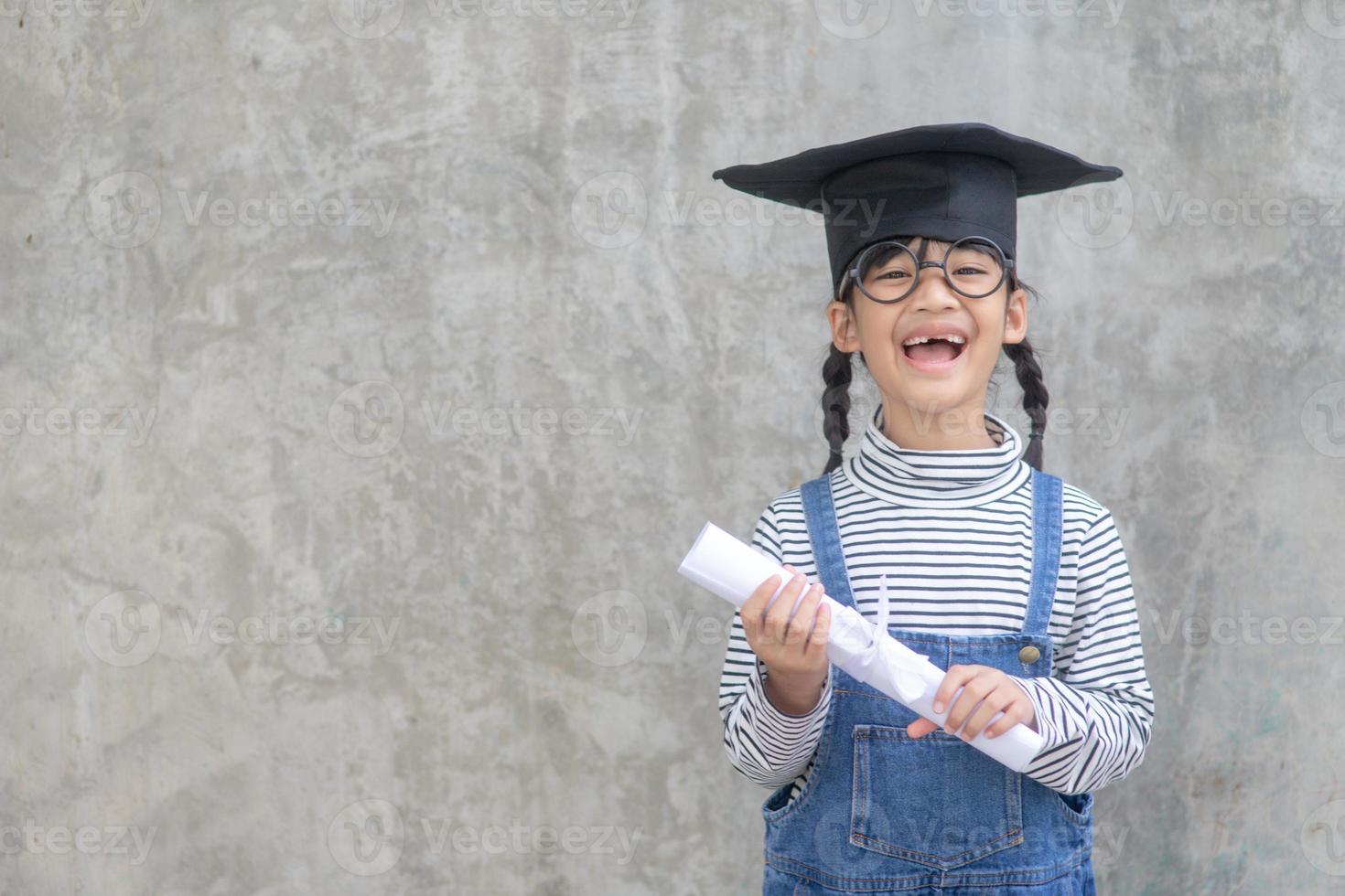 Happy Asian school kid graduate in graduation cap photo