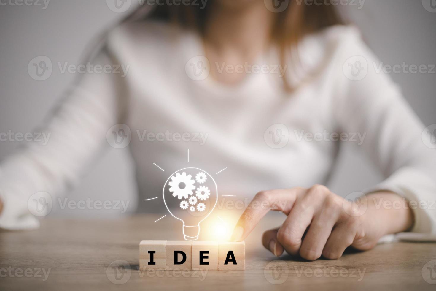 hand touching on light bulb on wood block with Word Idea, new idea concept with innovation and inspiration, innovative technology in science and communication concept. photo