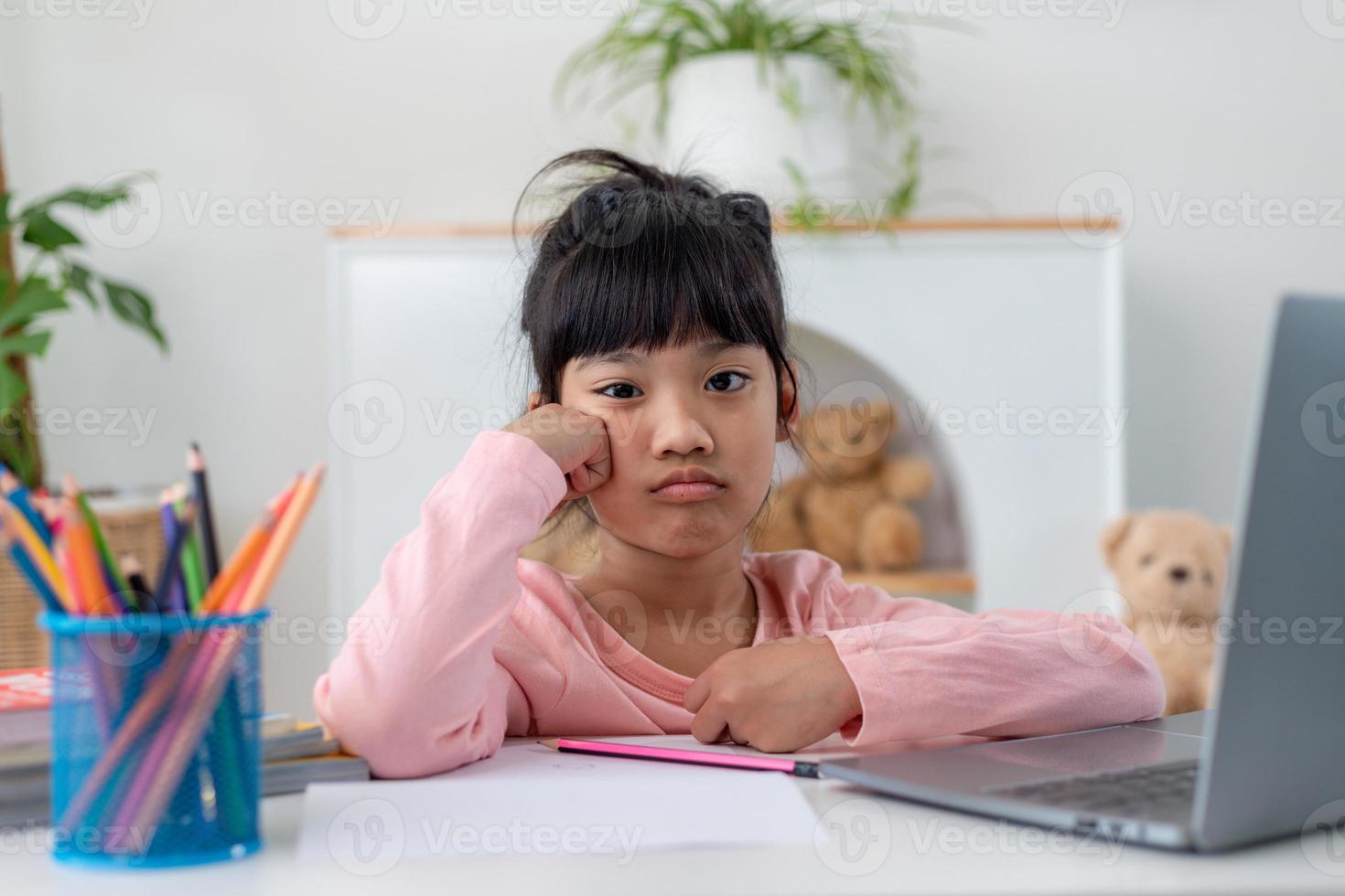 Unhappy little Caucasian girl child sit at table at home feel lazy unmotivated doing homework assignment. Upset distressed small 7s kid prepare school task, learn study with books. Education concept. photo