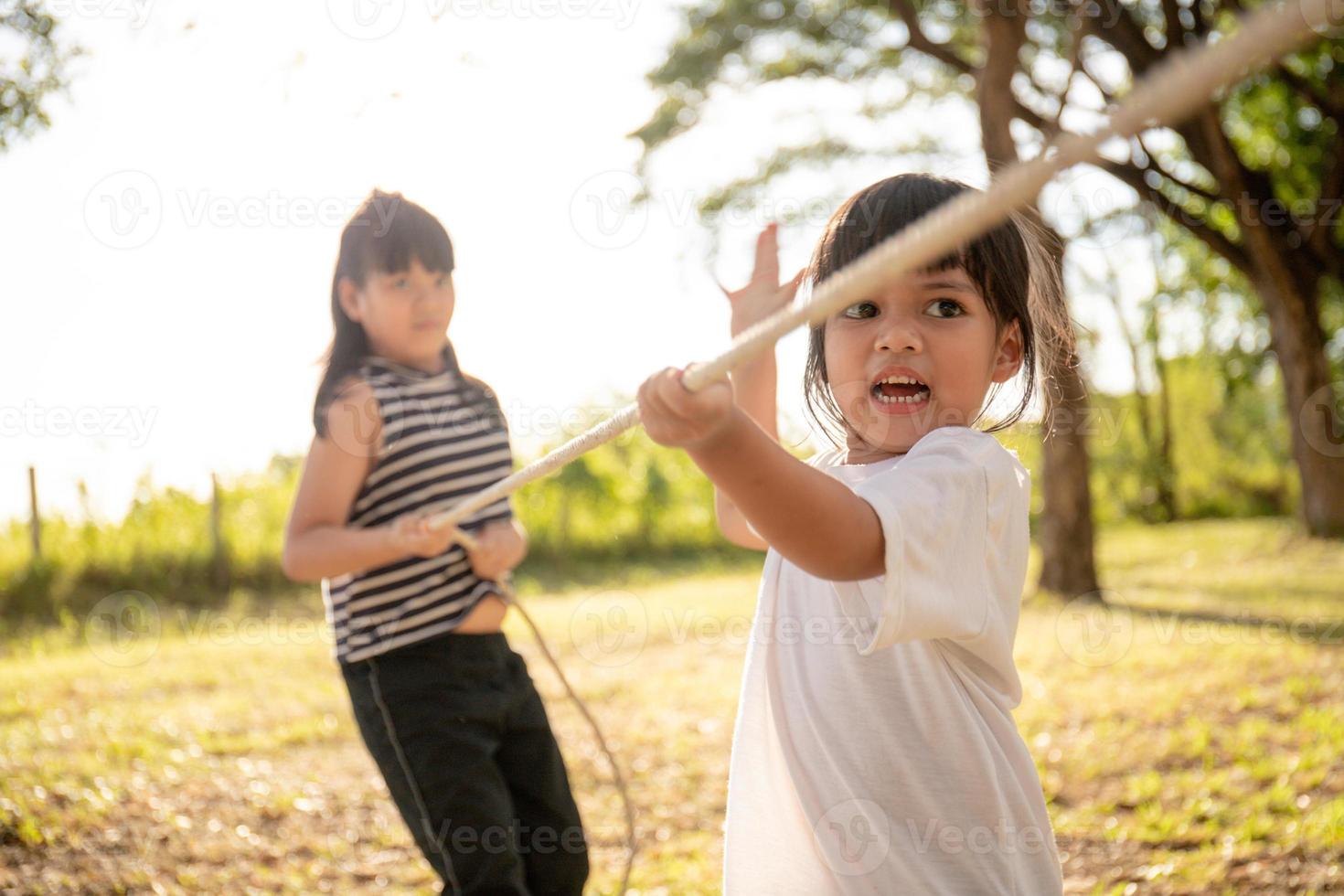 Children playing tug of war at the park on sunsut photo