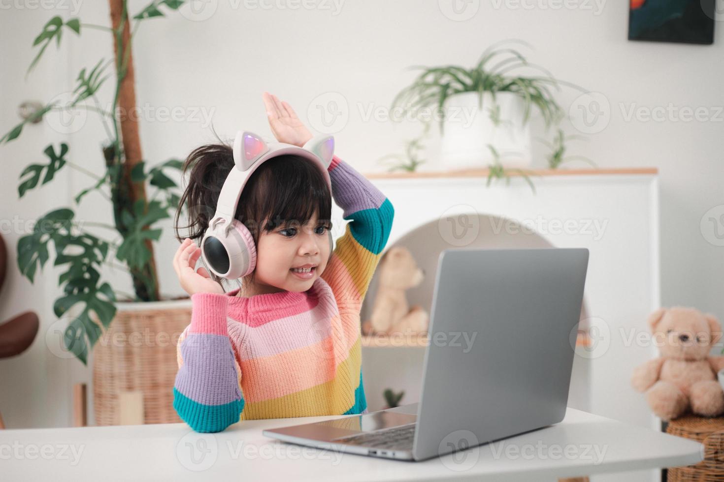 Smiling little Asian girl have a video call distant class with teacher using laptop, social distance during quarantine isolation during the Coronavirus photo