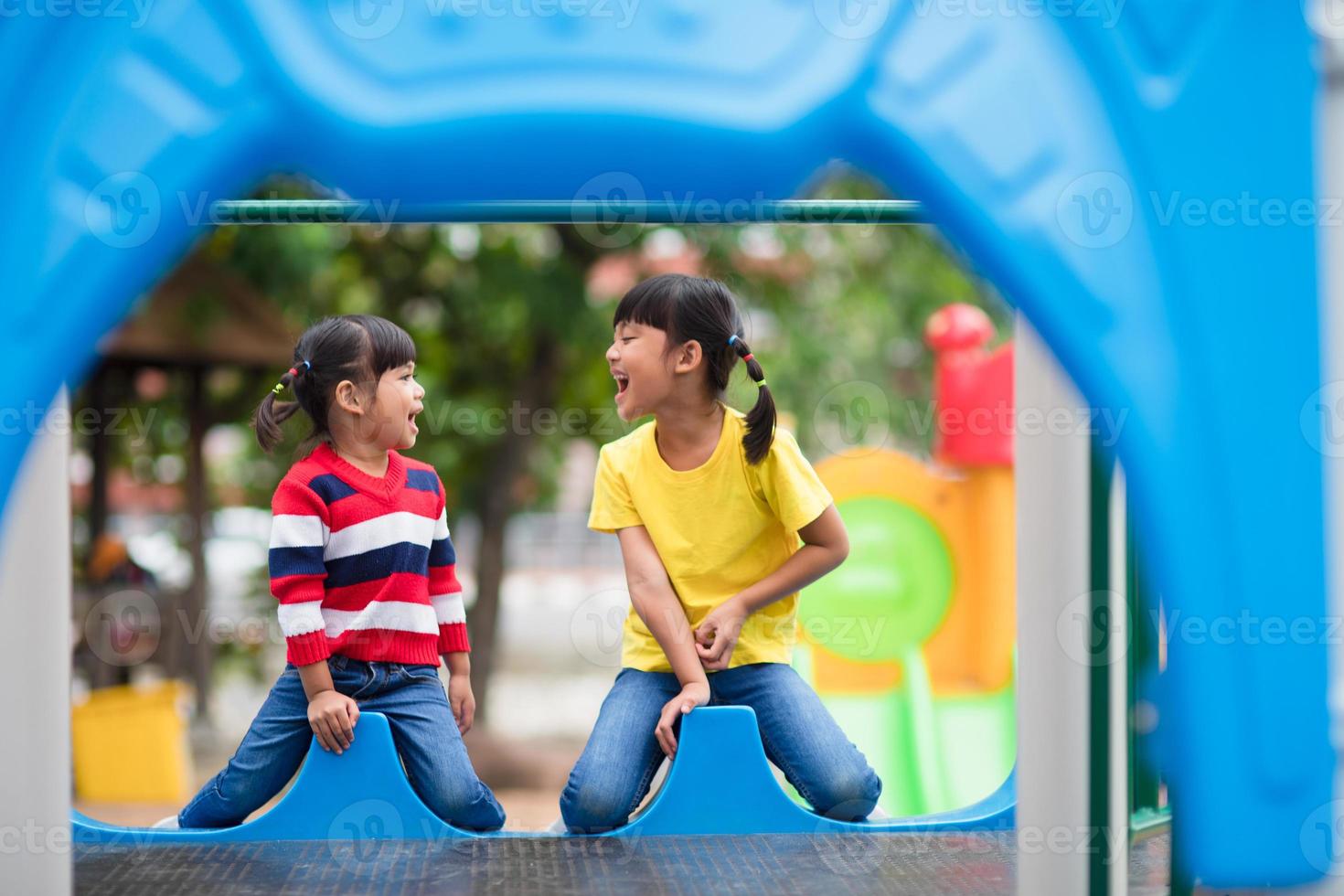 Cute little girls siblings having fun on playground outdoors on sunny summer day photo