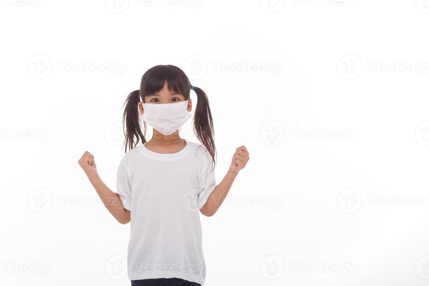 asia girl wearing mask to protect against Coronavirus, girl show a fist encourage to fight contagious disease concept stop virus Covid 19 outbreak to win on white background photo