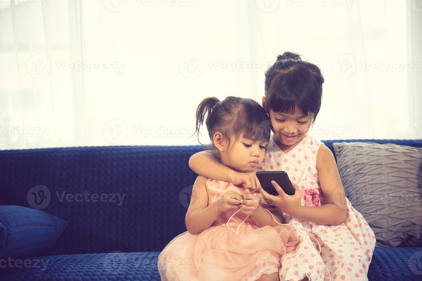 Children listening to music while sitting on a couch photo